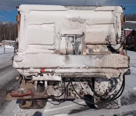 An image of a PennDOT plow truck all covered with snow, slush and dirt following a winter weather event.